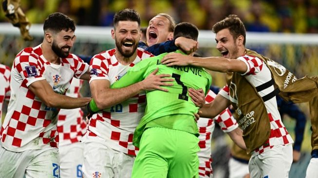 Kiper Timnas Kroasia, Dominik Livakovic (kedua kanan) melakukan selebrasi bersama rekan-rekan setimnya usai adu penalti laga perempat final Piala Dunia 2022 kontra Brasil di Stadion Education City, Al Rayyan, Qatar, Sabtu (10/12/2022) dini hari WIB.[GABRIEL BOUYS / AFP]