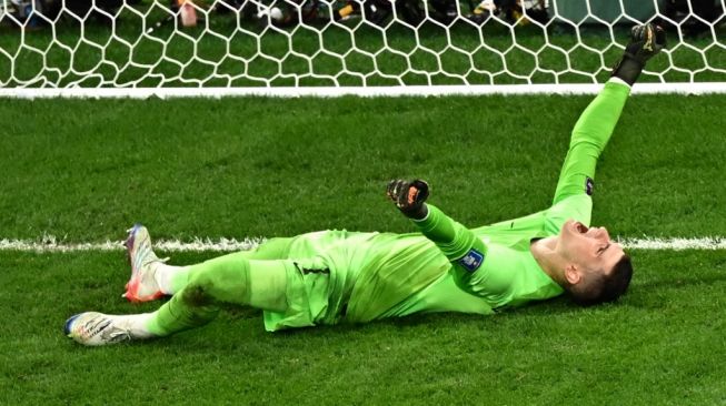 Kiper Timnas Kroasia, Dominik Livakovic melakukan selebrasi usai adu penalti laga perempat final Piala Dunia 2022 kontra Brasil di Stadion Education City, Al Rayyan, Qatar, Sabtu (10/12/2022) dini hari WIB. [Anne-Christine POUJOULAT / AFP]