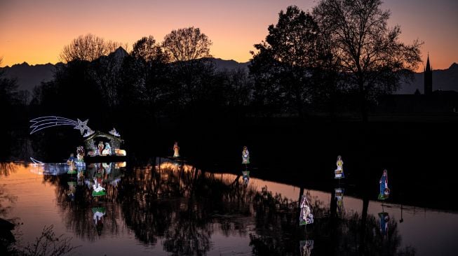 Warga saat akan memasang Instalasi Natal yang berkisah tentang kelahiran Yesus di sungai Po, Villafranca Piemonte, Turin, Italia, Selasa (6/12/2022). [MARCO BERTORELLO / AFP]
