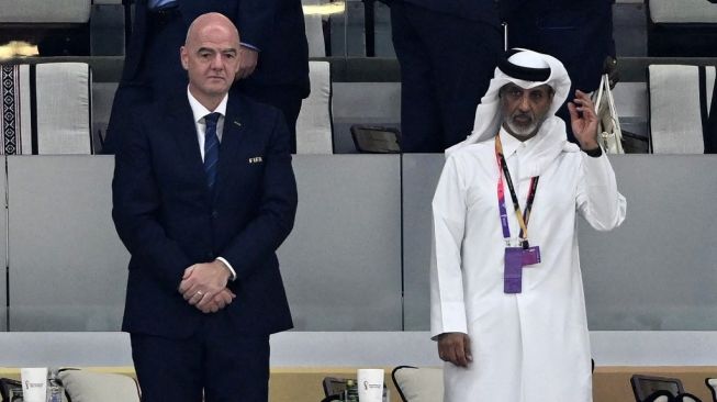 Presiden FIFA Gianni Infantino (kiri) dan Presiden Federasi Sepak Bola Qatar Hamad bin Khalifa berdiri saat mendengarkan lagu kebangsaan jelang laga Inggris vs Senegal di 16 besar Piala Dunia, 4 Desember 2022. [AFP]