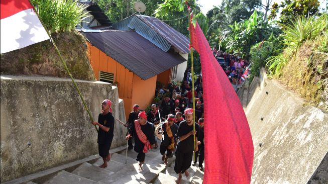 Sejumlah warga berjalan bersama sambil membawa bendera tanah (kanan) dan bendera merah putih saat puncak tradisi Cuci Negeri di Negeri (Desa) Soya, Kota Ambon, Provinsi Maluku, Jumat (9/12/2022). [ANTARA FOTO/FB Anggoro/nz]
