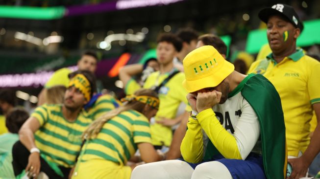 Pendukung Brazil terlihat sedih setelah timnya kalah dalam pertandingan sepak bola perempat final Piala Dunia 2022 antara Kroasia dan Brazil di Stadion Education City di Al-Rayyan, barat Doha, Qatar, Jumat (9/12/2022). [ADRIAN DENNIS / AFP]
