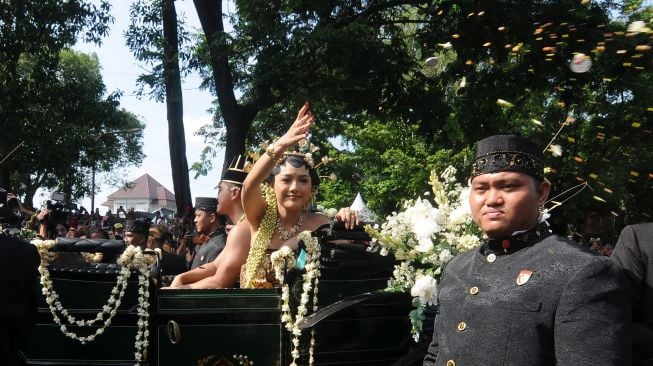 Pengantin putri yang juga menantu Presiden Joko Widodo, Erina Gudono (kedua kanan) menyebar "udik-udik" atau sarana berupa uang, beras dan bunga saat mengikuti prosesi kirab di Jalan Slamet Riyadi, Solo, Jawa Tengah, Minggu (11/12/2022). [ANTARA FOTO/Aloysius Jarot Nugroho].