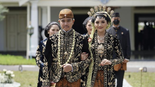 Putra bungsu Presiden Joko Widodo, Kaesang Pangarep (kiri) bersama Erina Gudono (kanan) berjalan menuju lokasi resepsi Tasyakuran di Pura Mangkunegaran, Solo, Jawa Tengah, Minggu (11/12/2022). [ANTARA FOTO/Dhemas Reviyanto].