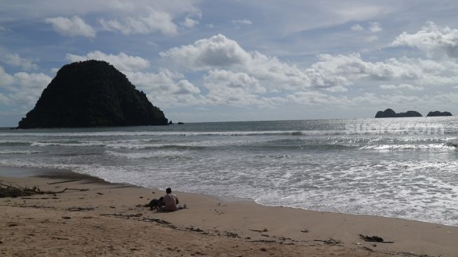 Asyiknya main pasir di Pantai Pulau Merah, salah satu objek wisata menarik di Banyuwangi, Jawa Timur, Kamis (1/12/2022). (Suara.com/Rima Sekarani)