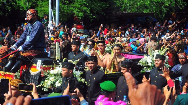 Pasangan pengantin Kaesang Pangarep dan Erina Gudono (tengah) menaiki kereta saat prosesi kirab Ngunduh Mantu di jalan Selamet Riyadi, Solo, Jawa Tengah, Minggu (11/12/2022). [ANTARA FOTO/Yusuf Nugroho]