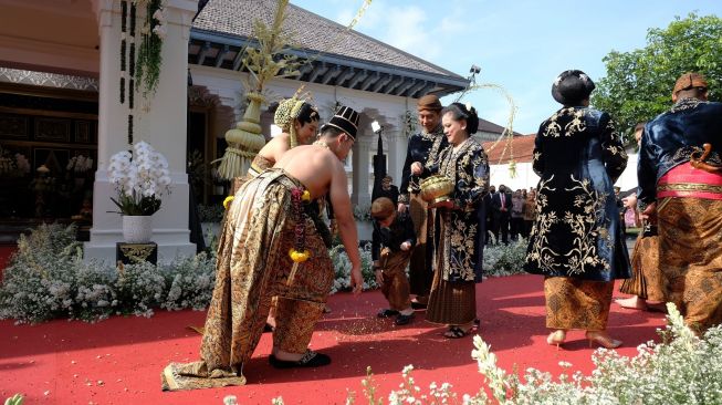 Presiden Joko Widodo (tengah) didampingi Ibu Negara Iriana Joko Widodo (ketiga kanan) dan keluarga mengikuti prosesi Udik-Udik atau menabur beras dan uang saat acara Ngunduh Mantu pernikahan putra bungsunya Kaesang Pangarep dengan Erina Gudono di Loji Gandrung Solo, Jawa Tengah, Minggu (11/12/2022). [ANTARA FOTO/Maulana Surya].