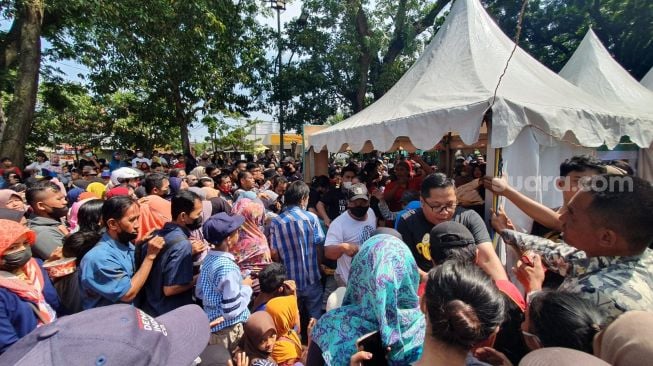 Warga berdesakan di stan makanan gratis yang berada di depan Stadion Sriwedari, Minggu (11/12/2022). [Suara.com/Hiskia]