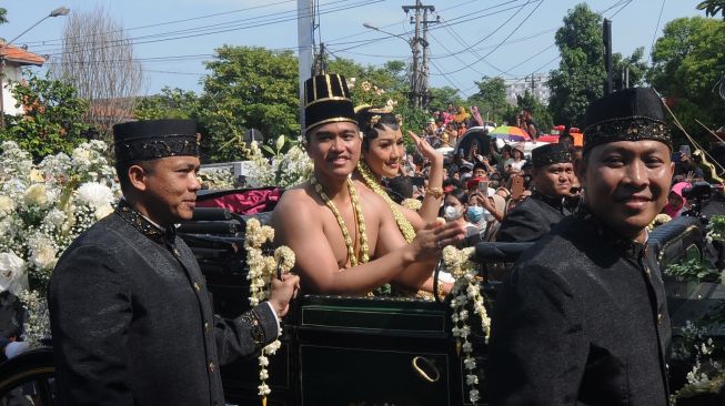 Putra bungsu Presiden Joko Widodo, Kaesang Pangarep (kedua kiri) bersama istrinya Erina Gudono (ketiga kiri) mengikuti prosesi kirab di Jalan Slamet Riyadi, Solo, Jawa Tengah, Minggu (11/12/2022). 
 [ANTARA FOTO/Aloysius Jarot Nugroho].