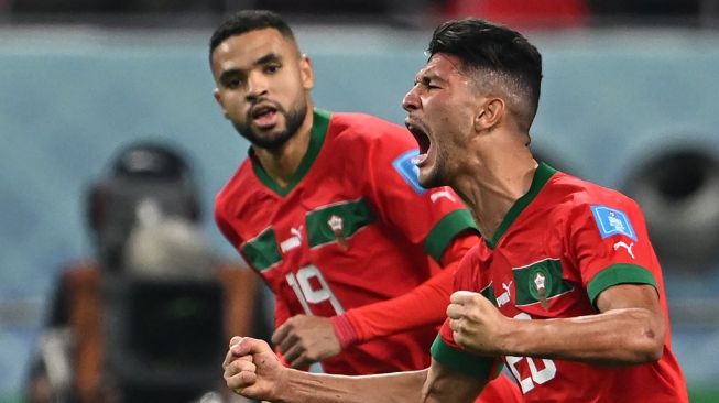 Bek timnas Maroko #20 Achraf Dari (kanan) melakukan selebrasi setelah mencetak gol penyama kedudukan selama pertandingan perebutan tempat ketiga Piala Dunia 2022 antara Kroasia vs Maroko di Stadion Internasional Khalifa di Doha pada 17 Desember 2022 .Paul ELLIS / AFP