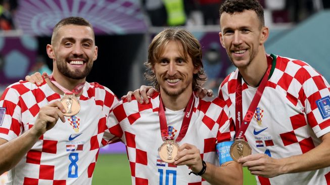 (Kiri-Kanan) Gelandang Kroasia Mateo Kovacic, Luka Modric dan Ivan Perisic memamerkan medali mereka setelah memenangkan pertandingan play-off perebutan tempat ketiga Piala Dunia 2022 antara Kroasia dan Maroko di Stadion Internasional Khalifa di Doha, Qatar, Sabtu (17/12/2022). [JACK GUEZ/AFP]