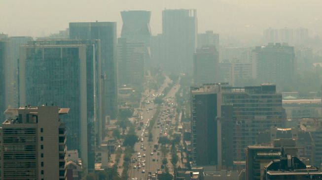 Pemandangan kota yang diselimuti asap dari kebakaran hutan yang melanda daerah sekitarnya di Santiago, Chili, Jumat (16/12/2022). [JAVIER TORRES / AFP]