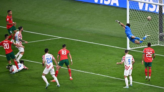 Bek Kroasia Josko Gvardiol (kiri di lapangan) mencetak gol melewati kiper Maroko Yassine Bounou saat pertandingan play-off perebutan tempat ketiga Piala Dunia 2022 antara Kroasia dan Maroko di Stadion Internasional Khalifa di Doha, Qatar, Sabtu (17/12/2022).[Anne-Christine POUJOULAT/AFP]