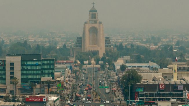 Pemandangan kota yang diselimuti asap dari kebakaran hutan yang melanda daerah sekitarnya di Santiago, Chili, Jumat (16/12/2022). [JAVIER TORRES / AFP]