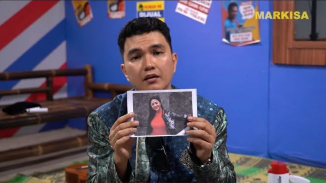 Aldi Taher memegang foto Dewi Perssik sebelum mengantongi ke dalam saku celananya (YouTube/Opra Entertainment)