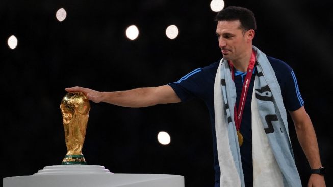 Pelatih Timnas Argentina, Lionel Scaloni menyentuh trofi Piala Dunia usai membawa timnya juara Piala Dunia 2022 pasca mengalahkan Prancis dalam laga final di Stadion Lusail, Qatar, Senin (19/12/2022) dini hari WIB. [FRANCK FIFE / AFP]