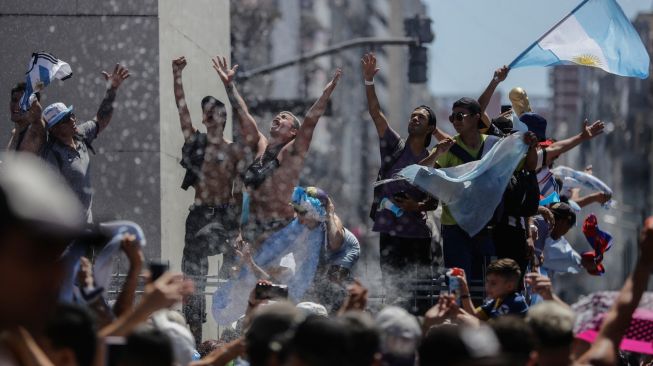 Fans Argentina berkumpul di Tugu Obelisk untuk merayakan kemenangan Piala Dunia Qatar 2022 melawan Prancis di Buenos Aires, Argentina, Minggu (18/12/2022). [Emiliano Lasalvia / AFP]