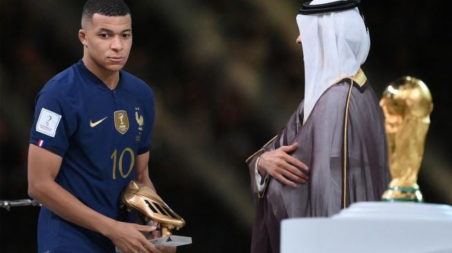 Penyerang Prancis Kylian Mbappe memegang Sepatu Emasnya saat ia menerima medali perak pada upacara trofi Piala Dunia 2022 Qatar setelah pertandingan final sepak bola antara Argentina dan Prancis di Stadion Lusail di Lusail, utara Doha, Qatar, Minggu (18/12/2022). [FRANCK FIFE / AFP]