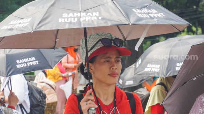 Sejumlah Ibu Pekerja Rumah Tangga (PRT) melakukan aksi Rabuan PRT: Payung Duka Seribu Ibu-Ibu PRT Indonesia di Taman Aspirasi Monas, Jakarta Pusat, Rabu (21/12/2022). [Suara.com/Alfian Winanto]