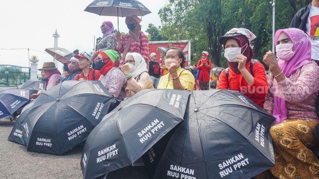 Sejumlah Ibu Pekerja Rumah Tangga (PRT) melakukan aksi Rabuan PRT: Payung Duka Seribu Ibu-Ibu PRT Indonesia di Taman Aspirasi Monas, Jakarta Pusat, Rabu (21/12/2022). [Suara.com/Alfian Winanto]