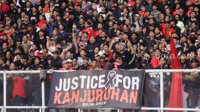 Suporter Indonesia membentangkan spanduk terkait Tragedi Kanjuruhan saat pertandingan sepak bola Grup A Piala AFF 2022 antara Indonesia dan Kamboja di Stadion Utama Gelora Bung Karno (SUGBK), Jakarta Pusat, Jumat (23/12/2022). [Suara.com/Alfian Winanto]