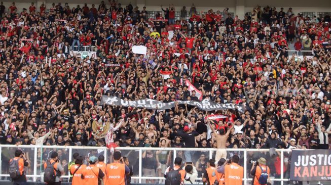 Suporter Indonesia membentangkan spanduk terkait Tragedi Kanjuruhan saat pertandingan sepak bola Grup A Piala AFF 2022 antara Indonesia dan Kamboja di Stadion Utama Gelora Bung Karno (SUGBK), Jakarta Pusat, Jumat (23/12/2022). [Suara.com/Alfian Winanto]