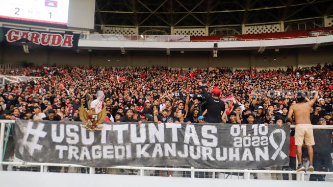 Suporter Indonesia membentangkan spanduk terkait Tragedi Kanjuruhan saat pertandingan sepak bola Grup A Piala AFF 2022 antara Indonesia dan Kamboja di Stadion Utama Gelora Bung Karno (SUGBK), Jakarta Pusat, Jumat (23/12/2022). [Suara.com/Alfian Winanto]