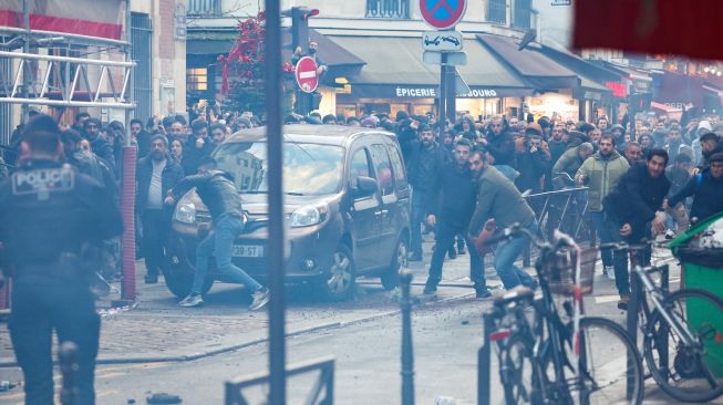 Para pengunjuk rasa bentrok dengan petugas polisi anti huru hara Prancis menyusul insiden penembakan kepada komunitas Suku Kurdi di Paris, Prancis, Jumat (23/12/2022). [Thomas SAMSON / AFP]