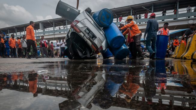 Sejumlah petugas mengevakuasi mobil yang jatuh ke laut di Dermaga II Pelabuhan Merak, Kota Cilegon, Banten, Sabtu (24/12/2022). [ANTARA FOTO/Muhammad Bagus Khoirunas/YU]