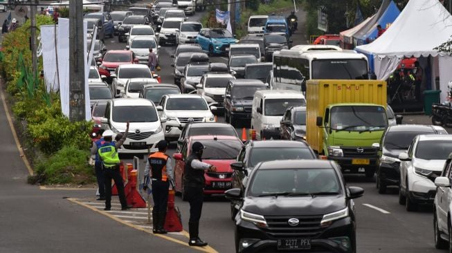 Sejumlah anggota Satlantas Polres Bogor bersama Dishub Kabupaten Bogor mengatur arus lalu lintas kendaraan yang memasuki Simpang Gadog, Ciawi saat diberlakukannya sistem satu arah menuju jalur wisata Puncak, Kabupaten Bogor, Jawa Barat, Sabtu (24/12/2022). [ANTARA FOTO/Arif Firmansyah/YU]