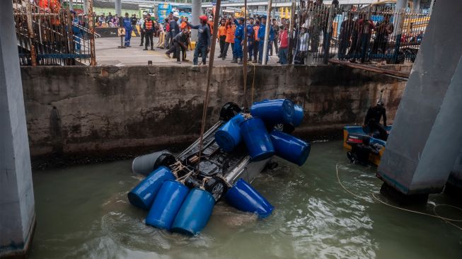 Sejumlah petugas menggunakan alat berat saat mengevakuasi mobil yang jatuh ke laut di Dermaga II Pelabuhan Merak, Kota Cilegon, Banten, Sabtu (24/12/2022). [ANTARA FOTO/Muhammad Bagus Khoirunas/YU]