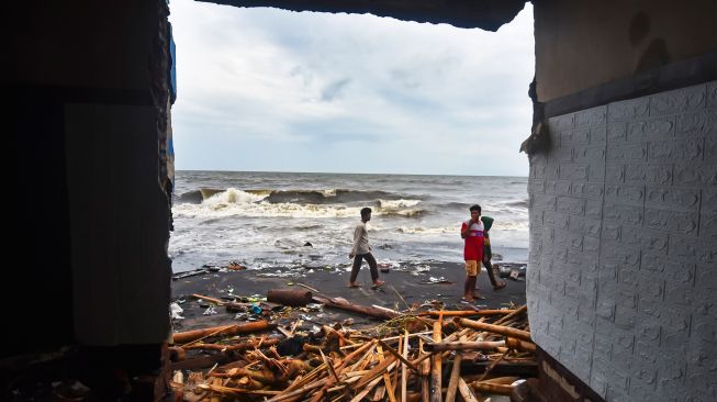 Sejumlah warga melintas di dekat bangunan rumah yang roboh di Lingkungan Mapak Indah, Kelurahan Jempong Baru, Mataram, NTB, Sabtu (24/12/2022). [ANTARA FOTO/Ahmad Subaidi/YU]