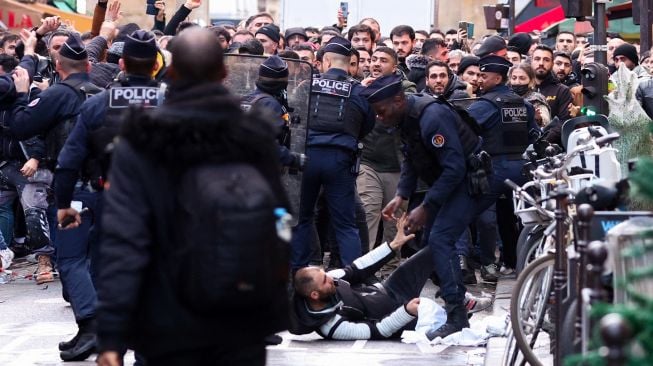 Para pengunjuk rasa bentrok dengan petugas polisi anti huru hara Prancis menyusul insiden penembakan kepada komunitas Suku Kurdi di Paris, Prancis, Jumat (23/12/2022). [Thomas SAMSON / AFP]