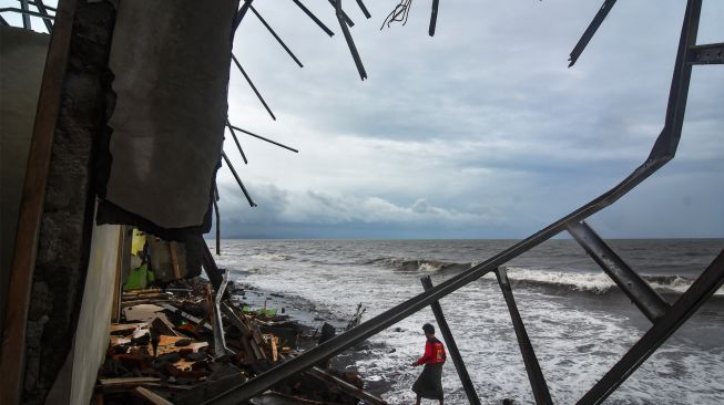 Warga melintas di dekat bangunan rumah yang roboh di Lingkungan Mapak Indah, Kelurahan Jempong Baru, Mataram, NTB, Sabtu (24/12/2022). [ANTARA FOTO/Ahmad Subaidi/YU]