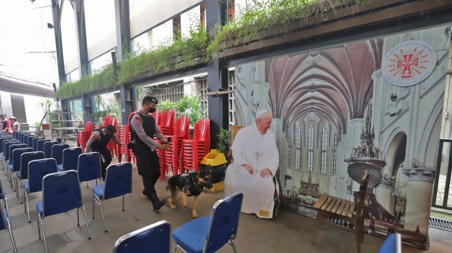 Personel kepolisian membawa anjing pelacak saat melakukan sterilisasi dan pengamanan di Gereja Katedral, Jakarta Pusat, Sabtu (24/12/2022). [Suara.com/Alfian Winanto]