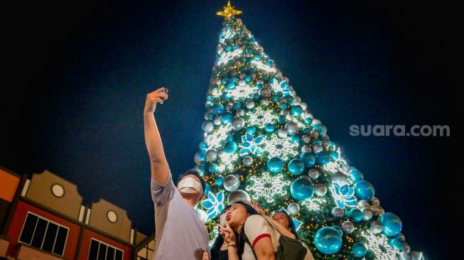 Warga berfoto dengan background pohon natal di kawasan La Riviera di Pantai Indah Kapuk (PIK 2), Kabupaten Tangerang, Banten, Minggu (25/12/2022).  [SuaraSerang/Wawan Kurniawan]