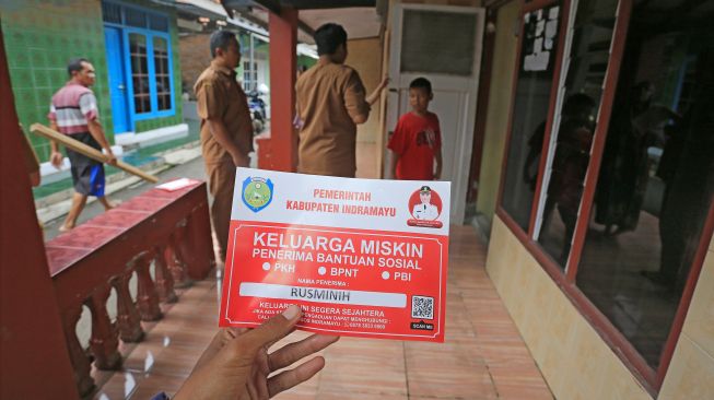 Petugas bersiap menempelkan stiker Keluarga Miskin di salah satu rumah Keluarga Penerima Manfaat (KPM) bantuan sosial di Indramayu, Jawa Barat, Senin (26/12/2022). [ANTARA FOTO/Dedhez Anggara].