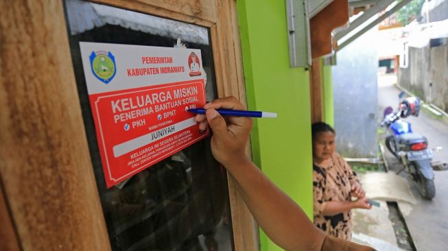 Petugas menempelkan stiker Keluarga Miskin di salah satu rumah Keluarga Penerima Manfaat (KPM) bantuan sosial di Indramayu, Jawa Barat, Senin (26/12/2022). [ANTARA FOTO/Dedhez Anggara].