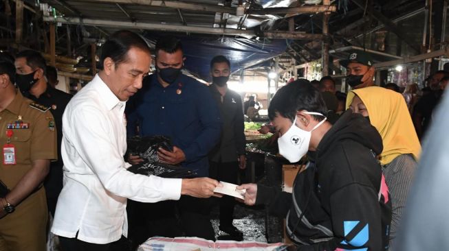 Presiden Joko Widodo (Jokowi) didampingi Ibu Negara Iriana memberikan bantuan sosial (bansos) kepada para pedagang yang ada di Pasar Baru, Kabupaten Subang, Jawa Barat, Selasa (27/12/2022). [Foto: Kris - Biro Pers Sekretariat Presiden]