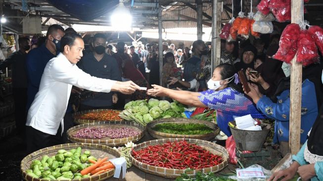 Presiden Joko Widodo (Jokowi) didampingi Ibu Negara Iriana memberikan bantuan sosial (bansos) kepada para pedagang yang ada di Pasar Baru, Kabupaten Subang, Jawa Barat, Selasa (27/12/2022). [Foto: Kris - Biro Pers Sekretariat Presiden]