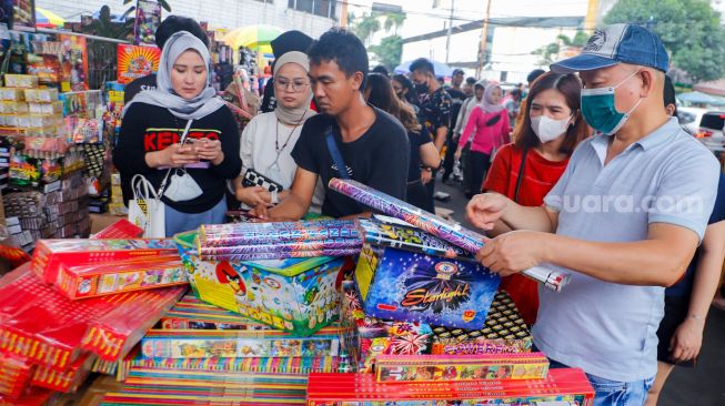 Pedagang kembang api melayani pembeli di Pasar Asemka, Jakarta Barat, Jumat (30/12/2022). [Suara.com/Alfian Winanto]