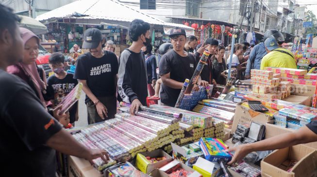 Pedagang kembang api melayani pembeli di Pasar Asemka, Jakarta Barat, Jumat (30/12/2022). [Suara.com/Alfian Winanto]