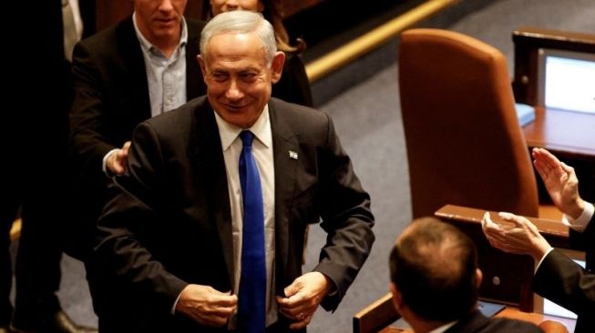 Perdana Menteri Israel Benjamin Netanyahu tersenyum ketika pemerintah baru Israel yang beraliran kanan dilantik di Knesset --parlemen Israel-- di Yerusalem, Kamis (29/12/2022). [Antara/Reuters/Amir Cohen/tm]