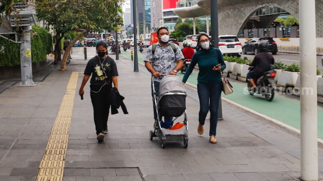 Warga melintas saat jam pulang kerja di kawasan Bundaran Hotel Indonesia (HI), Jakarta Pusat, Jumat (30/12/2022). [Suara.com/Alfian Winanto]