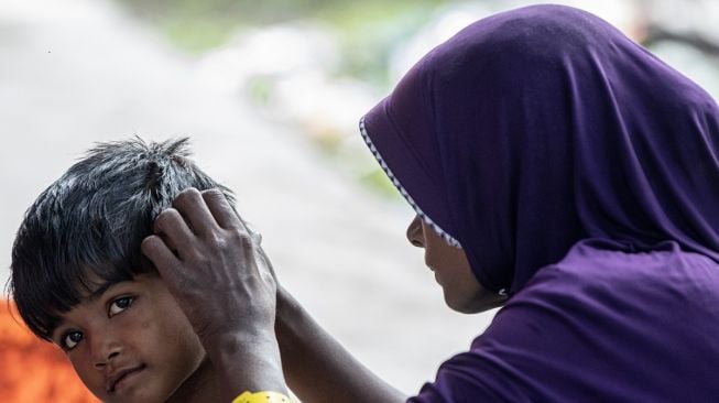 Imigran etnis Rohingya bersama anaknya berada di lokasi penampungan sementara di SMP Negeri 2 Curei, Gampong Curei, Kecamatan Muara Tiga, Kabupaten Pidie, Aceh, Jumat (30/12/2022).[ANTARA FOTO/Nova Wahyudi]