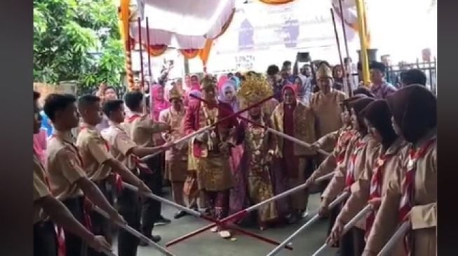 Bukan dengan Pedang, Tongkat Pora Jadi Sambutan Bagi Pasangan yang Menikah dengan Tema Pramuka Ini