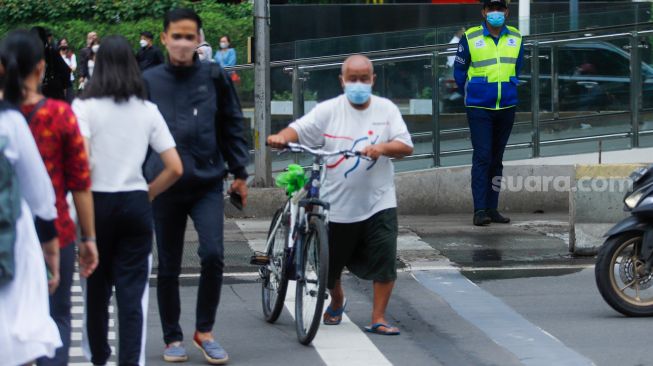 Warga melintas saat jam pulang kerja di kawasan Bundaran Hotel Indonesia (HI), Jakarta Pusat, Jumat (30/12/2022). [Suara.com/Alfian Winanto]