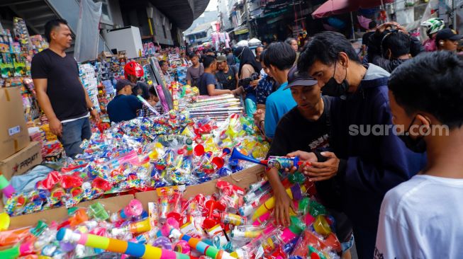 Pedagang Terompet melayani pembeli di Pasar Asemka, Jakarta Barat, Jumat (30/12/2022). [Suara.com/Alfian Winanto]