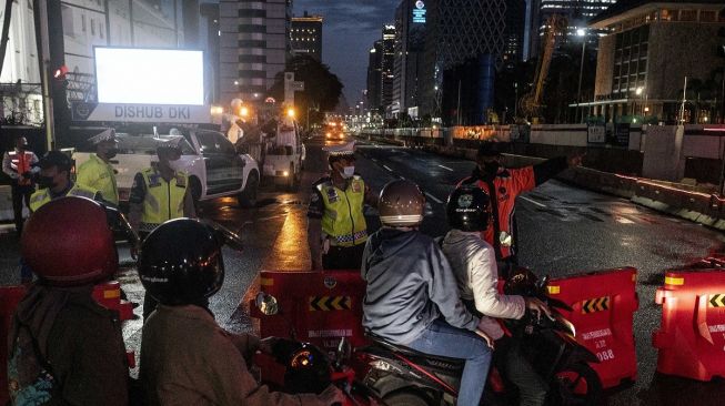 Petugas gabungan menyampaikan informasi kepada pengguna kendaraan bermotor terkait penutupan jalan di Jalan MH Thamrin, Jakarta, Sabtu (31/12/2022). [ANTARA FOTO/Aprillio Akbar].