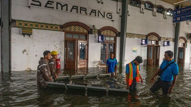 Petugas stasiun memindahkan kursi tunggu penumpang yang terendam banjir di selasar tunggu Stasiun Tawang, Semarang, Jawa Tengah, Sabtu (31/12/2022). [ANTARA FOTO/Aji Styawan].